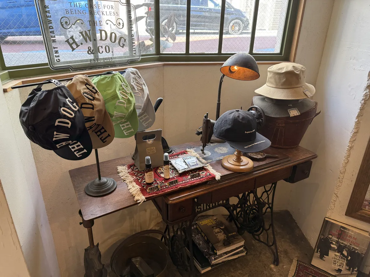 店の窓辺に、THE H.W.DOGのロゴ刺しゅうのキャップやバケットハット、ケア用品が並んでいる